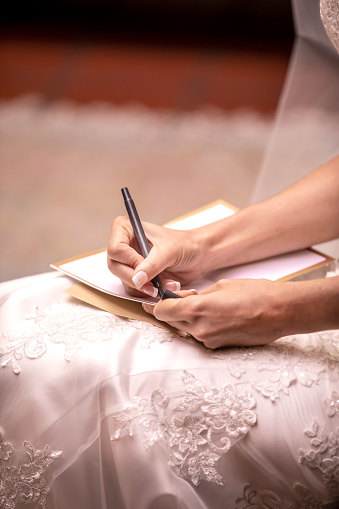 Wedding ceremony vows being written by a bride to be on a pad of paper