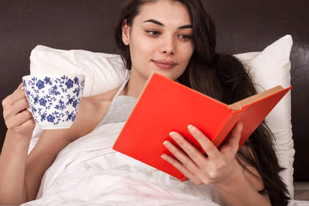 istock young woman reading book on bed 1219054366