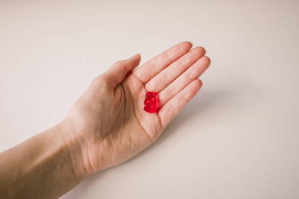 Gummy bear A red gummy bear in a hand on a white background cannabis gummy bears stock pictures, royalty-free photos & images