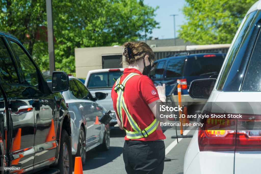 Wedding Photography at Piedmont Park in Atlanta, GA. Kennesaw, GA / USA - 04/02/20: Young youthful fast food worker working at Chick-fil-a drive through amidst cars take orders with tablet. Chick-Fil-A Stock Photo