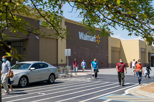 Kennesaw, GA / USA - 04/05/20: Walmart line outside the store with masked people practicing social distancing 6 feet apart during Covid-19 Corona Virus Pandemic.