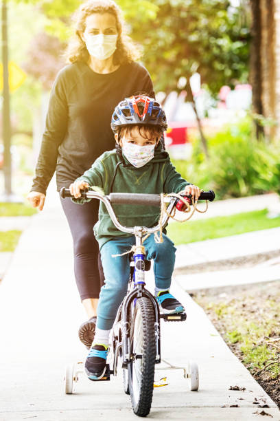 istock Mature woman helping her son riding a bicycle wearing a protective mask 1219058265