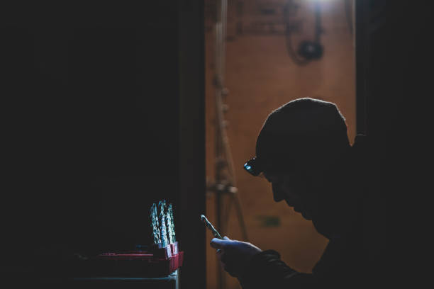 istock Silhouette of carpenter with headlamp choosing drill bit in the dark 1219060060