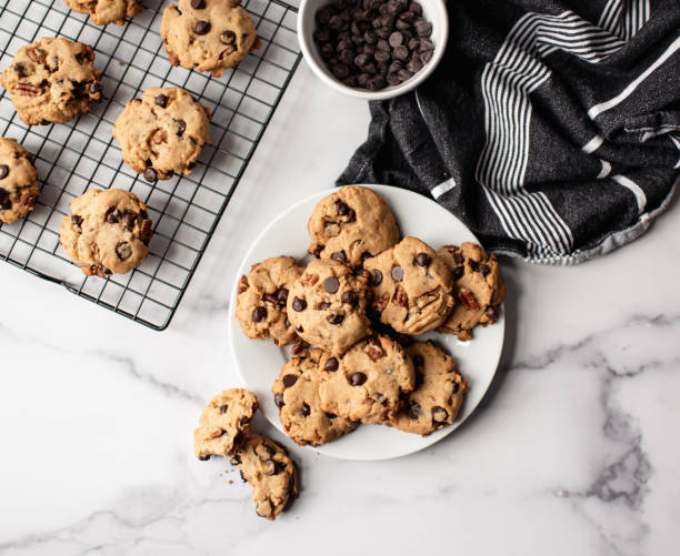 vista superior dos biscoitos de chocolate em um prato no balcão de mármore branco. - cookie chocolate chocolate chip chocolate chip cookie - fotografias e filmes do acervo