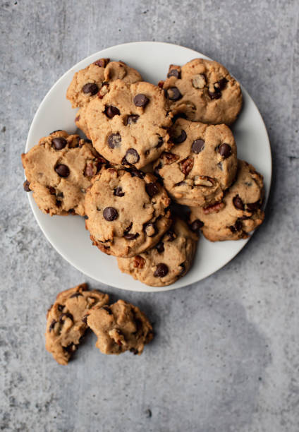 cierre de las galletas de chocolate recién horneadas en el plato de arriba. - chocolate chip cookie cookie preparing food chocolate fotografías e imágenes de stock