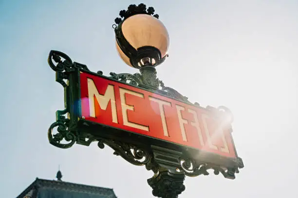 Photo of Paris Metro sign with sunflare against blue sky