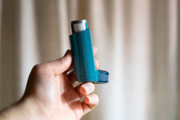istock Hand picking up a blue asthma inhaler. 1219060882