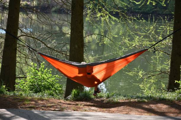 persona che si rilassa su un'amaca accanto a un lago nel parco - piedmont park foto e immagini stock
