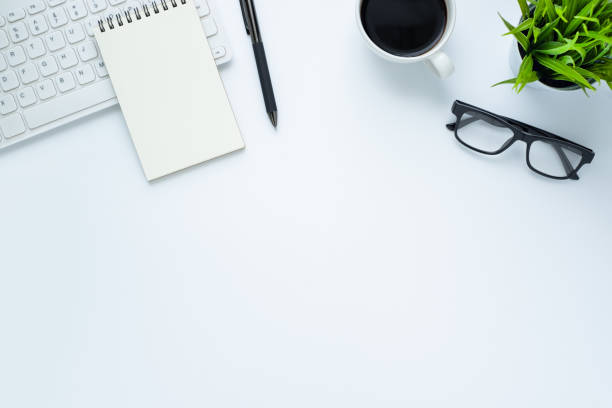 istock Workplace in office with white desk. Top view from above of keyboard with notebook and coffee. Space for modern creative work of designer. Flat lay with blank copy space. Business and finance concept. 1219080098