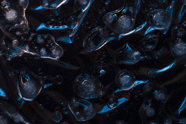 istock Melting ice and water droplets are illuminated with blue light against a dark background. Close-up. 1219082707