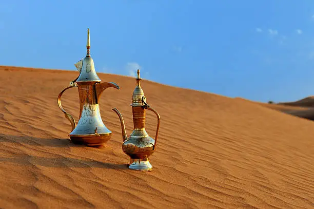 typical traditional arabic tea or coffee pots on desert under blue sky.