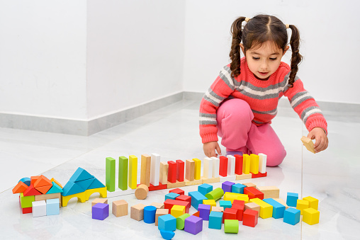 Cute toddler play with zero waste toys, different color and shape wooden toy building blocks.