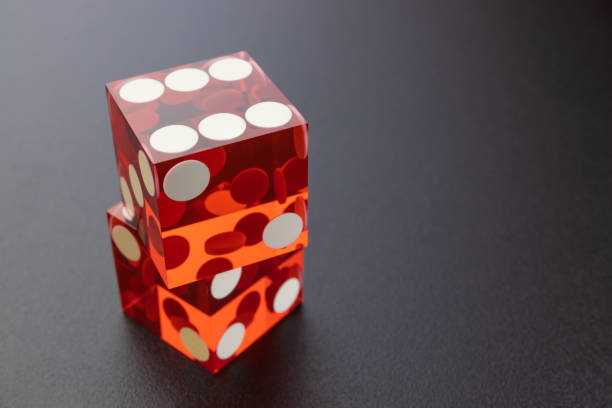 istock Two red glass dice on a black matte background with side lighting. Dice on the other, on top six. 1219087639