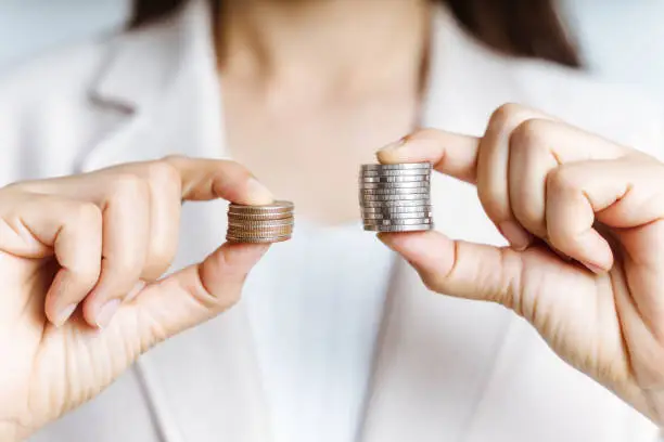 Photo of Hands compare two piles of coins of different sizes.