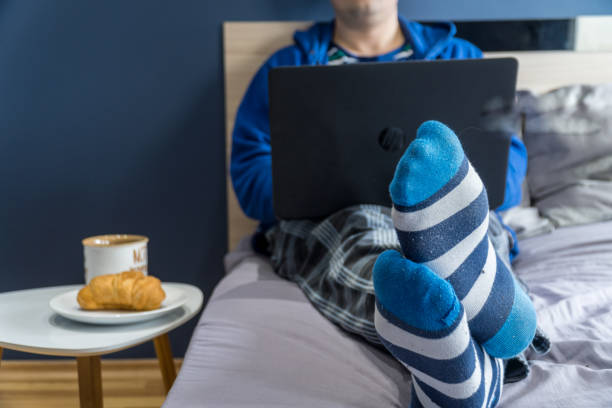 Home office concept - man working from his bed with breakfast stock photo