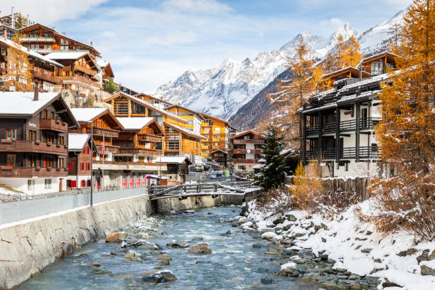 Old town with rocky stream of Zermatt, Switzerland. Zermatt, Switzerland - November 11, 2019: Landscape of old town with rocky stream alongside wooden houses and resorts, environment covered by snow in winter. pennine alps stock pictures, royalty-free photos & images