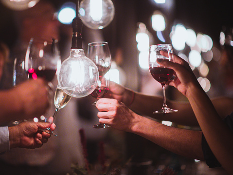 Multiple people Light Bulb Celebratory Toast with red wine and champagne selective focus