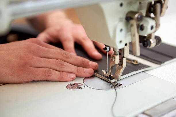 istock The craftsman sews a black strip on gray wallet with special sewing machine. 1219106128