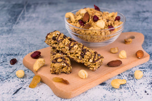 Granola bars and granola in a plate with nuts, berries and raisins on a wooden board. The concept of healthy and dietary breakfasts. stock photo