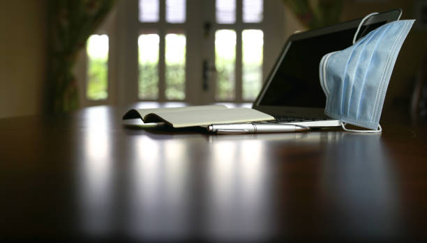 istock Medical face mask on computer laptop. Home setting. 1219108915