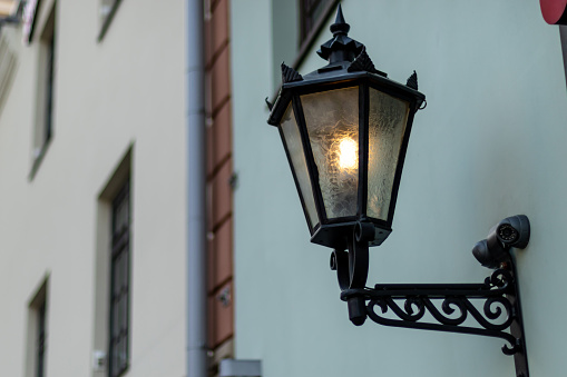 Old fashioned street lamp at night. Brightly lit street lamps at sunset. Decorative lamps. Magic lamp with a warm yellow light in the city twilight