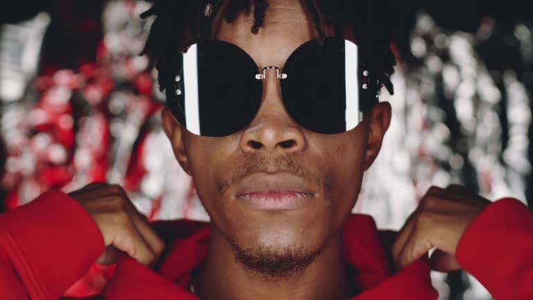 Young Black Man in Sunglasses Taking off Hood and Posing for Camera