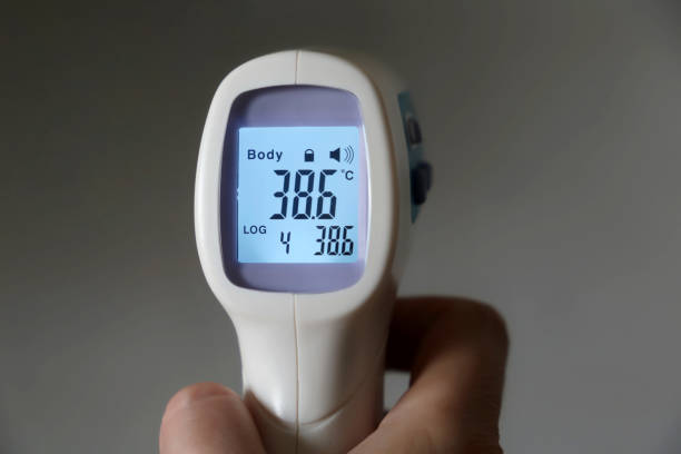 High body temperature, digital display of isometric non-contact thermometer in hand Concept of covid-19 coronavirus symptoms covid thermometer stock pictures, royalty-free photos & images