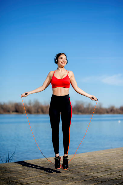 istock Young women jump roping by river 1219118351
