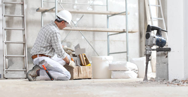 l'operaio edile lavora con guanti per l'usura della scatola degli utensili, elmetto e occhiali di protezione nel cantiere interno con impalcature. secchio e sacchi - plaster plasterer wall repairing foto e immagini stock