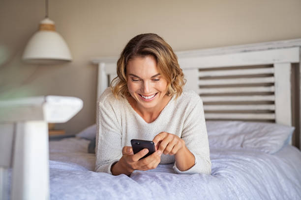 istock Happy woman lying on bed using phone 1219120323