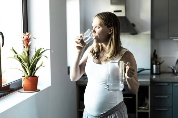 istock Pensive expectant mother standing in kitchen with jug 1219120779