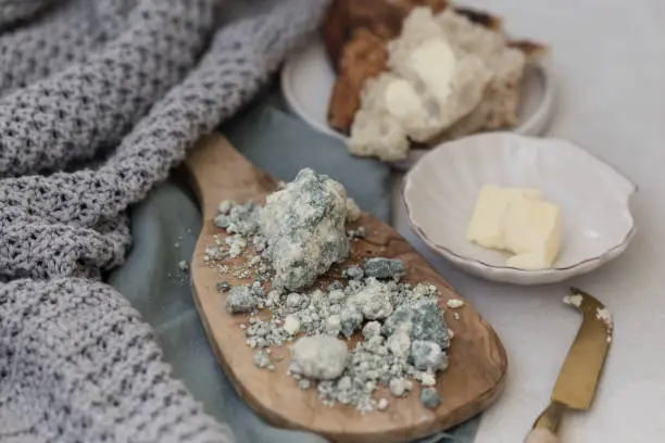 Horizontal image of blue lamb cheese placed on a wooden olive board with negative space in upper right corner of the image.