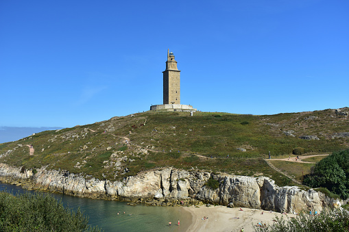 A Coruña, Coruña Province, Rias Altas, Galicia Region, Spain, Europe. Famous Torre de Hercules, roman lighthouse still in use. Summer view on a sunny day with beach, cliff and park.
