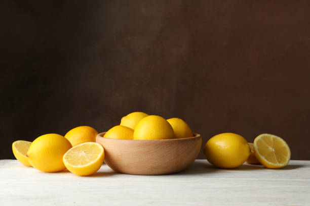 istock Wooden bowl and lemons against brown background, space for text 1219122435