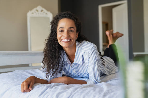 istock Happy mixed race woman lying on bed and looking at camera 1219125080