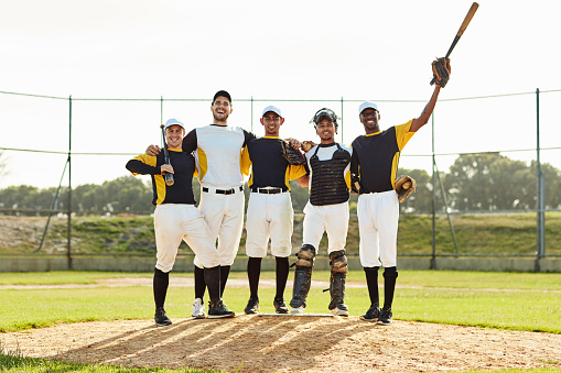 Full length shot of a team of baseball players posing together on the pitch during the day