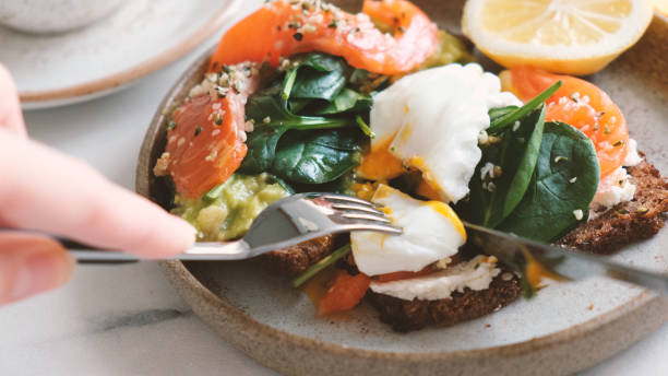 istock Eating toast with poached egg, salmon, avocado and spinach 1219127015