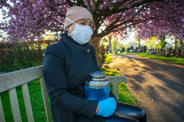 Photo of Covid-19 Female Mourner with Loved Ones Cremation Ashes in Funeral Urn