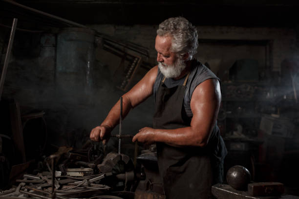istock Brutal blacksmith artisan in apron makes the product in the blacksmith 1219128578