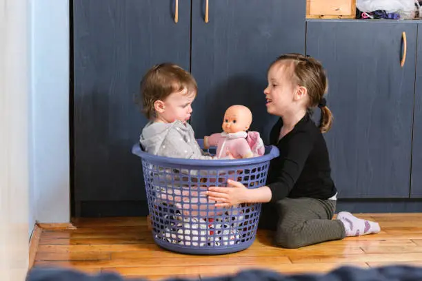 Children playing whit laundry basket indoors