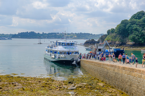Tourists walking towards the ferry at Île de Bréhat at the Côtes d'Armor in Bretagne France during a beautiful summer day. Ile de Brehat is a popluair tourist destination and a place to spend a vacation in one of the idyllic cottages.
