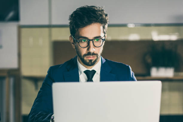 istock Front view of focused man in eyeglasses looking at laptop 1219131866