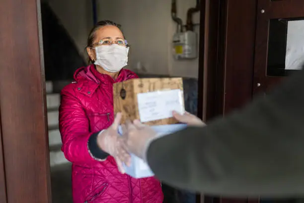 Photo of Senior woman getting a package from delivery person
