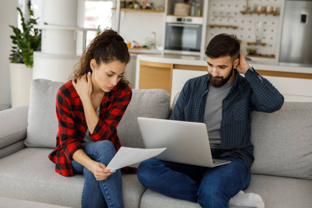 istock Young couple working on a budget while sitting on sofa in the living room 1219133292