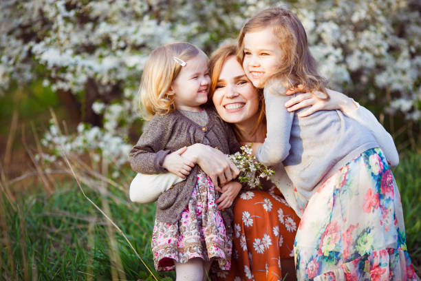 istock mom and daughters sitting in flowering shrub 1219134730