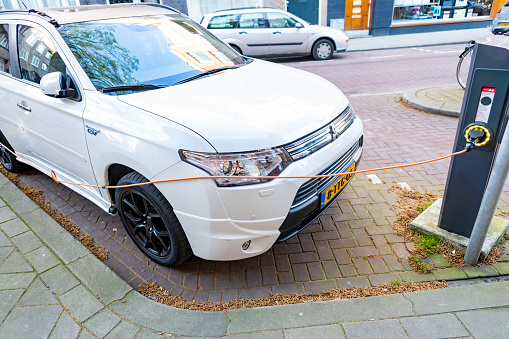 Mitsubishi Outlander PHEV hybrid vehicle using a public battery charger on an Amsterdam Street.