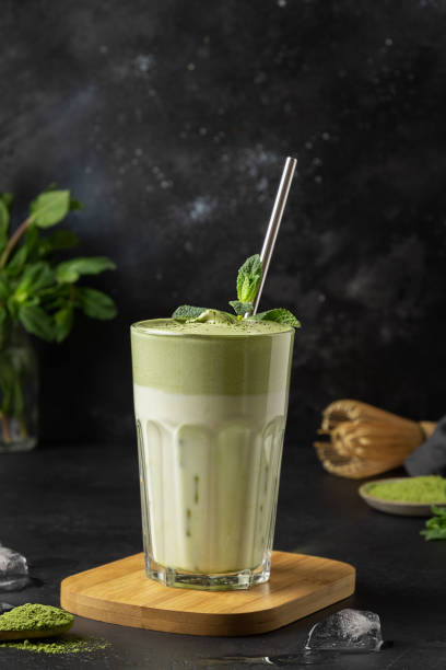 ダルゴナアイスティー抹茶のグラスは、黒にミントを飾ります。 - green tea ice tea ice cube mint ストックフォトと画像