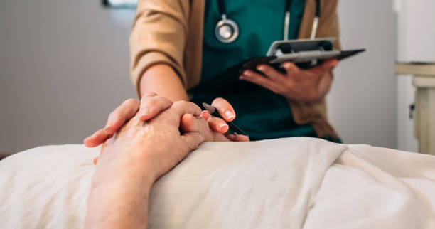Female doctor comforting older patient Unrecognizable young female doctor comforting unrecognizable older female patient personal care aid stock pictures, royalty-free photos & images
