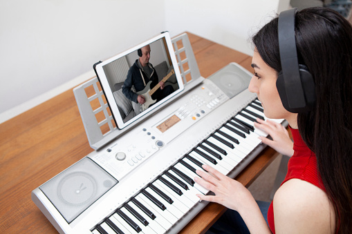 Piano player viewed from above making music with guitarist on a digital tablet