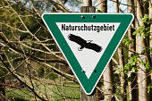 A green and white sign for a nature reserve on the edge of a forest on a sunny day in Rastatt, Germany